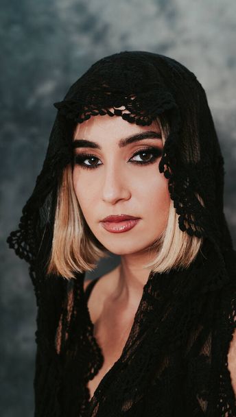 A portrait of a young blonde female with a black scarf on her head in a studio - Foto, imagen