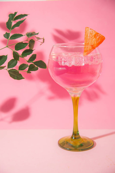 A vertical shot of a glass of gin and tonic on a pink background - Foto, Imagem