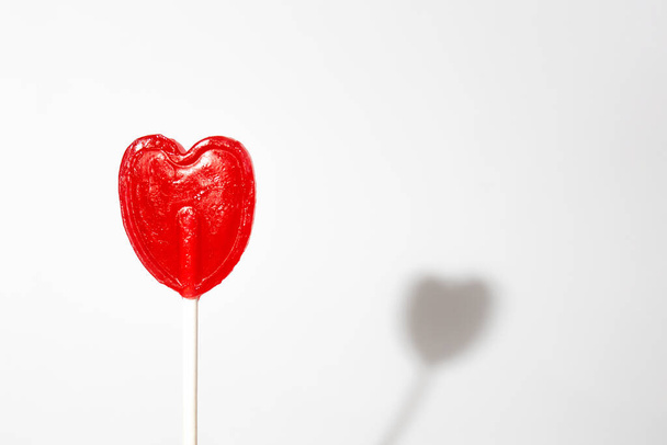 A closeup shot of a single heart-shaped lollipop on a white background - Фото, зображення