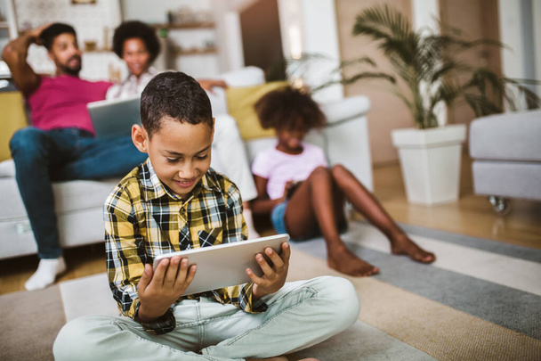 Ragazzo e ragazza afroamericani sdraiati sul pavimento e utilizzando tablet digitale. Famiglia a casa. - Foto, immagini