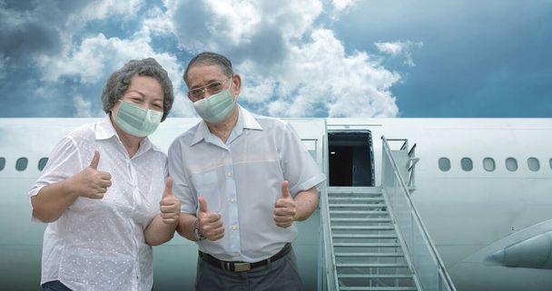 Бабушка и дедушка азиатского возраста уверены в себе и счастливы путешествовать в масках для защиты от пандемии коронавируса на самолете для хорошего путешествия. - Фото, изображение