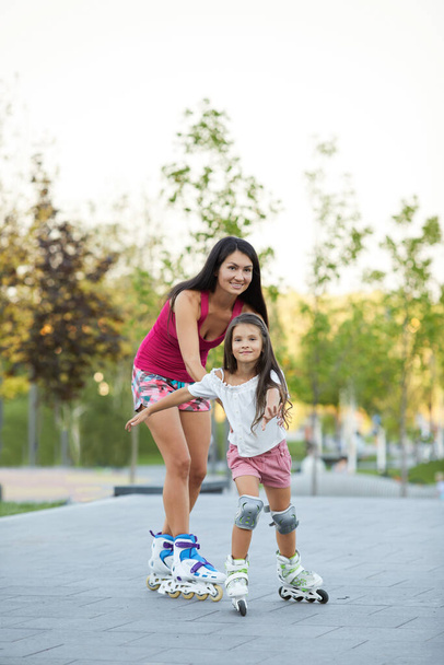 mother and her little daughter rollerskating - Foto, afbeelding