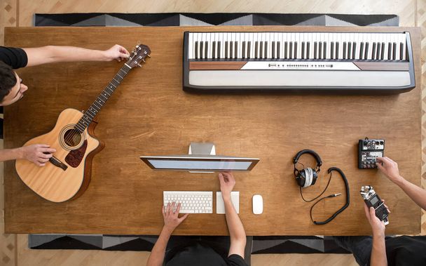 Настільна музична клавіатура, акустична гітара, звуковий мікшер, навушники, комп'ютер і чоловічі руки копіюють простір. Процес запису звуку
. - Фото, зображення