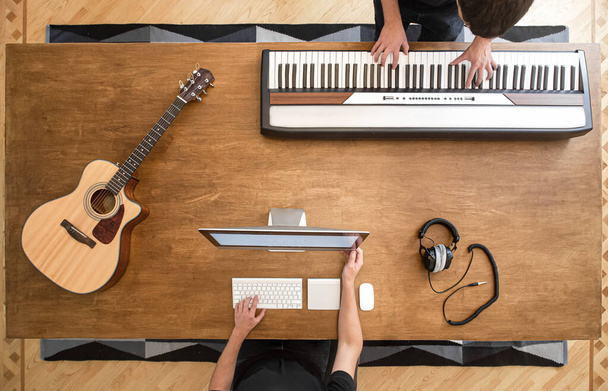 Музиканти створюють музику у своїй студії, граючи на клавішних. Процес запису звуку. Дерев'яний стіл на фоні копіювання простору
 - Фото, зображення