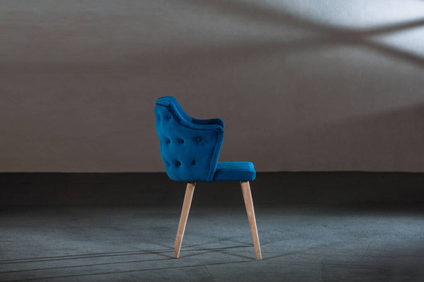 A comfy blue wing chair in a studio with gray walls - Fotografie, Obrázek