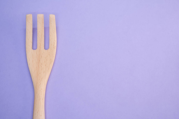 A high angle shot of a wooden fork on a purple surface - Fotoğraf, Görsel