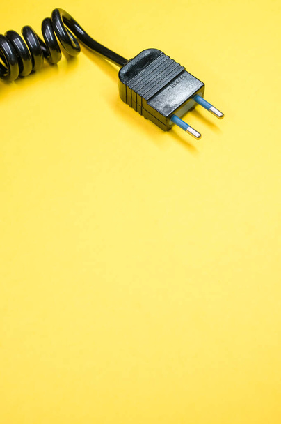 Un cable de alimentación negro sobre un fondo amarillo - Foto, Imagen