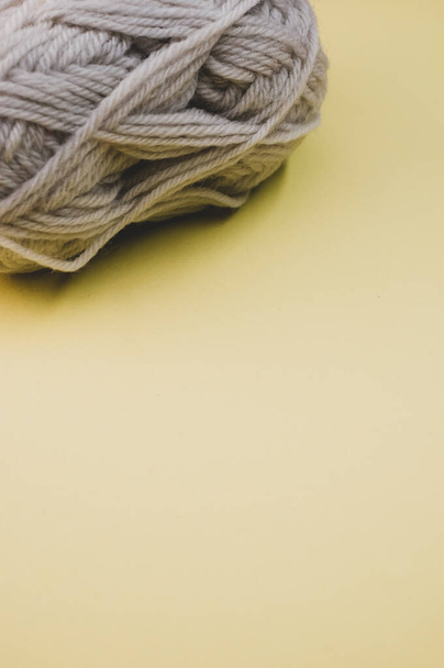A vertical shot of a ball of yarn on a yellow surface - Фото, зображення