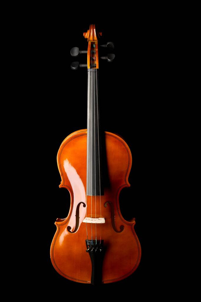 Brown wooden fiddle or violin, classic musical instrument, isolated over black background, flat lay top view from above - Fotó, kép
