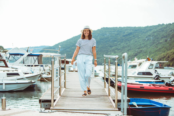 mujer en blanco vista de lujo de la moda caminando por los barcos del muelle en fondo. hora de verano - Foto, Imagen