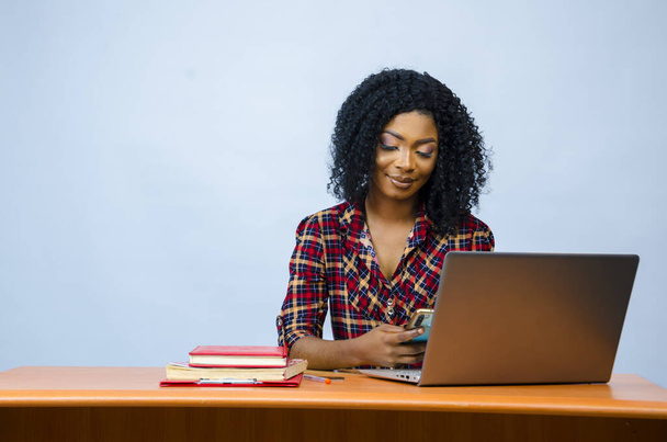 A pretty Afro-American female sitting in front of a laptop and working - Photo, Image