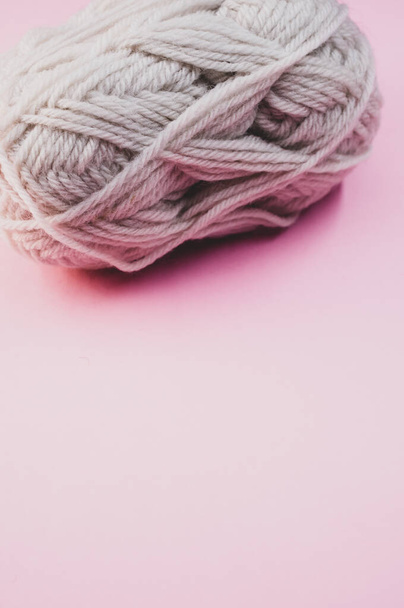 A vertical shot of a ball of yarn on a pink surface - 写真・画像