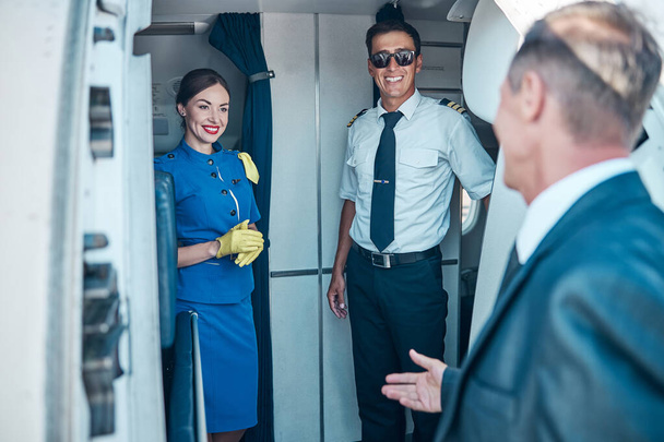 Улыбающаяся команда встречается с бизнесменом на пассажирском самолете - Фото, изображение