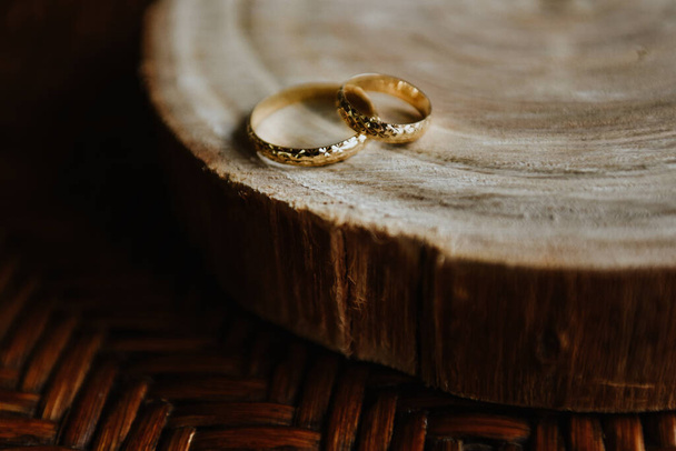 A closeup shot of the symbolic golden wedding rings on the wood - Fotó, kép
