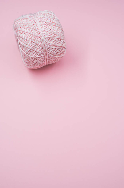A vertical shot of a ball of yarn on a pink surface - Photo, image