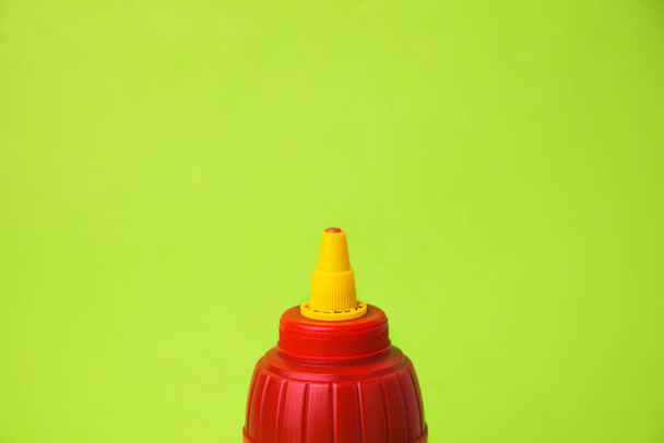 A closeup shot of a ketchup bottle on a green background - Fotoğraf, Görsel