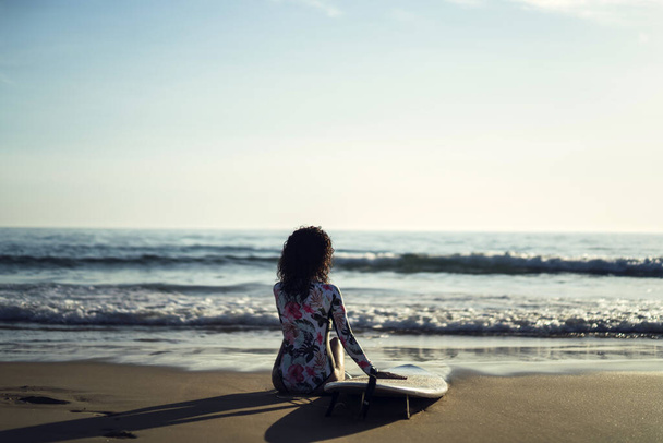A beautiful young surfer woman  with a surfboard having fun on the beach - Zdjęcie, obraz