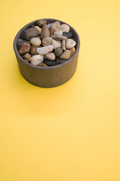 A vertical shot of a bowl filled with colorful rocks and pebbles - Valokuva, kuva