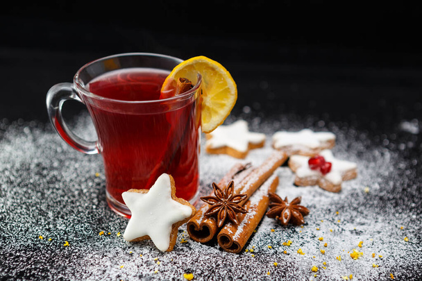 A selective focus shot of a cup of tea with delicious cookies, anise stars and cinnamon sticks - 写真・画像