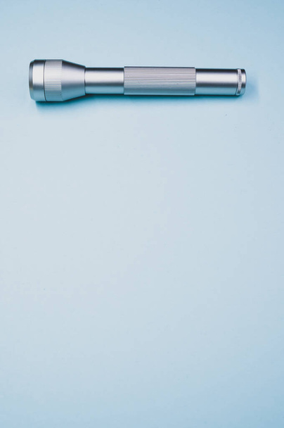 A silver flashlight on a light blue background - Foto, immagini