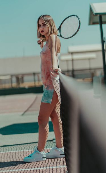 A shallow focus of a confident female with hair highlights holding a tennis racquet and posing at a court - Foto, immagini