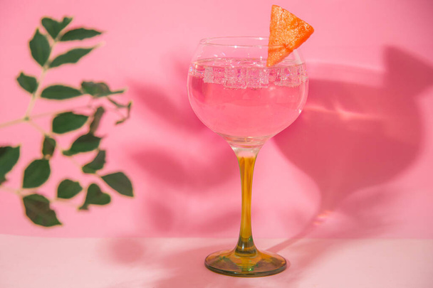 A glass of gin and tonic on a pink background - Foto, afbeelding