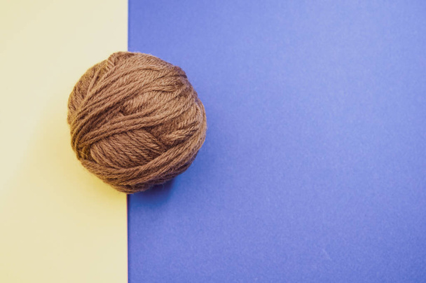 A high angle shot of a ball of yarn on a blue and yellow surface - Φωτογραφία, εικόνα