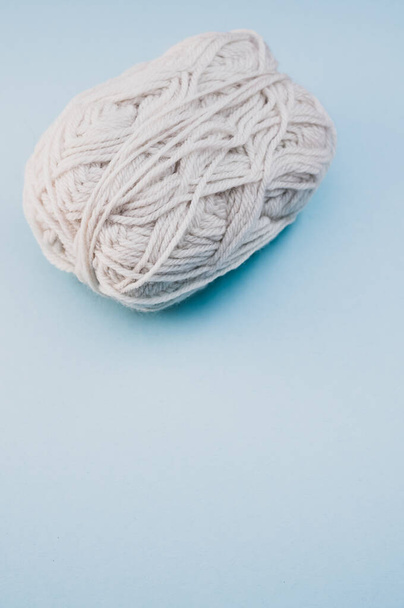 A vertical shot of a ball of yarn on a blue surface - Foto, Imagem