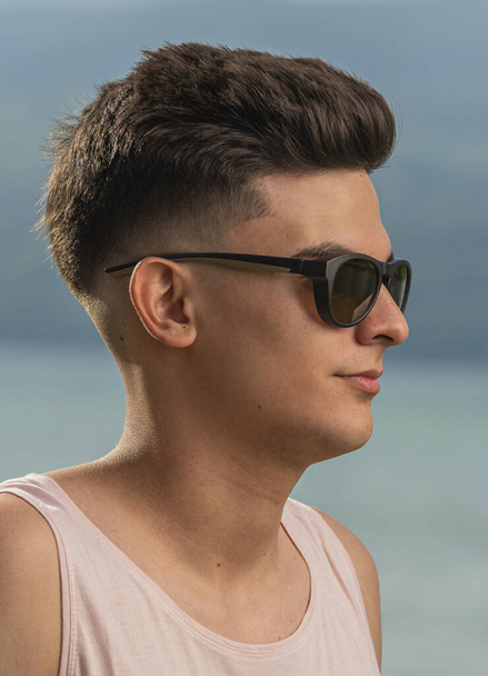 A closeup vertical portrait of a stunning young male with a perfect hairstyle wearing trendy sunglasses - Φωτογραφία, εικόνα
