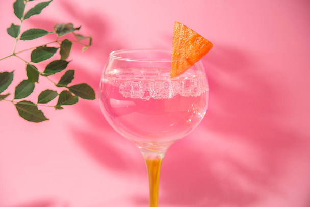 Een glas gin-tonic op een roze achtergrond - Foto, afbeelding