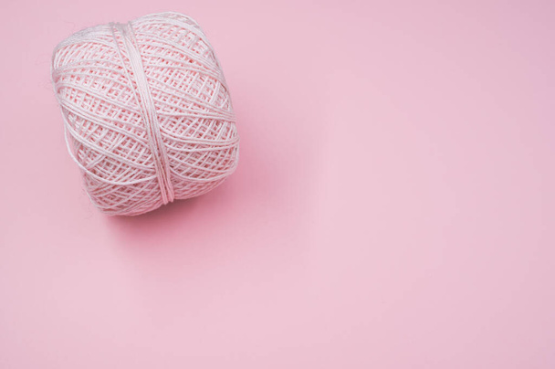 A high angle shot of a ball of yarn on a pink surface - Valokuva, kuva