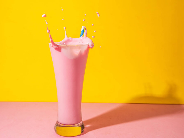 A glass of strawberry smoothie isolated on yellow and pink background - Photo, image