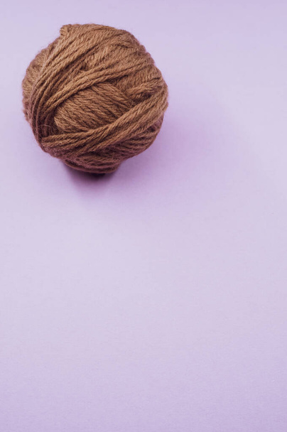 A vertical shot of a ball of yarn on a purple surface - Φωτογραφία, εικόνα