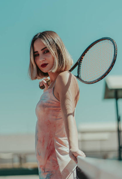 A shallow focus of a confident female with hair highlights holding a tennis racquet and posing at a court - Foto, Imagem