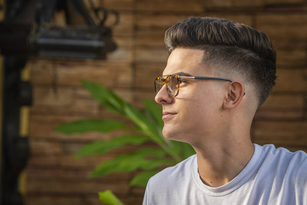 A closeup portrait of a handsome young man with a trendy hairstyle and transparent sunglasses - Fotografie, Obrázek