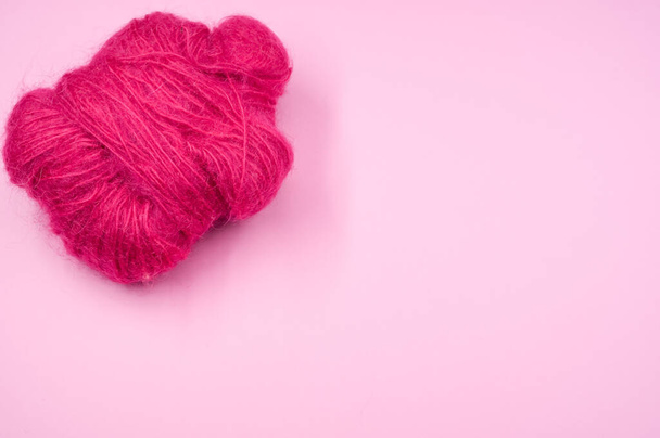 A high angle shot of a ball of pink yarn on a pink surface - Fotó, kép