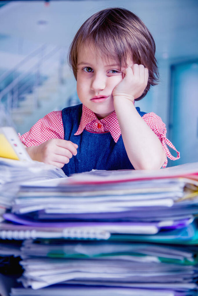 Humorous portrait of tired young business girl wants to sleep.  Exhausted child sitting in office with a lot of documents. Selective focus on eyes. Vertical image. - Photo, Image