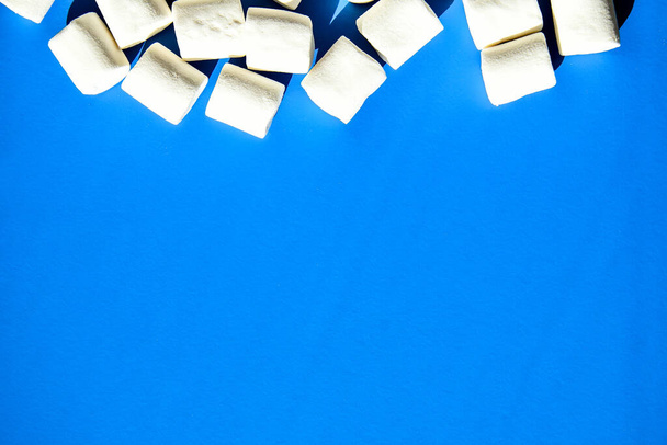 Marshmallows on blue background with Copy space. Flat lay. Top view. Background or texture of colorful mini marshmallows. Winter food background concept. Junk unheathy food. - Photo, Image