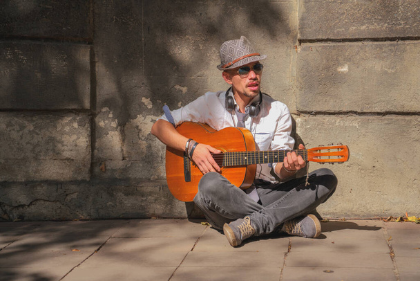 Hombre caucásico músico callejero tocando la guitarra al aire libre. Música, arte, creatividad. - Foto, Imagen