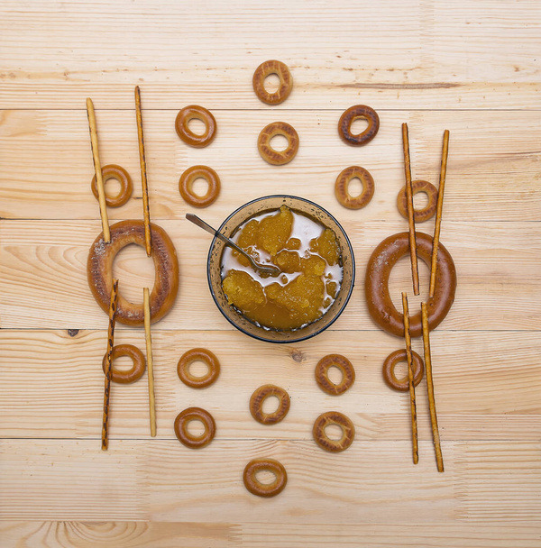 Uma xícara com mel de abelha, secagem e palhas de pão estão em uma mesa de madeira - Foto, Imagem