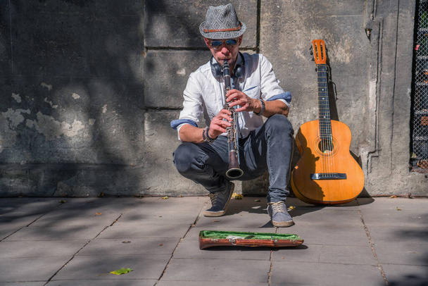 Ein Straßenmusiker spielt auf einem Bürgersteig in der Stadt Musik mit Klarinette. - Foto, Bild