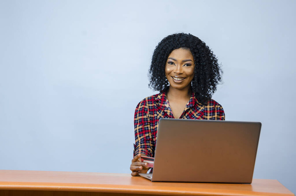 A pretty Afro-American female sitting in front of a laptop and working - Foto, immagini