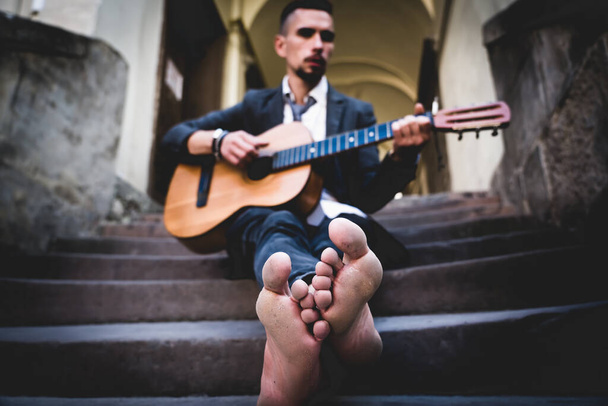 Straßenmusiker, der draußen Gitarre spielt. Selektiver Fokus auf die Füße. Musik, Kunst, Kreativität. - Foto, Bild