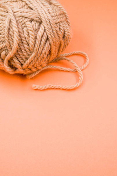 A vertical shot of a ball of yarn on an orange surface - Zdjęcie, obraz
