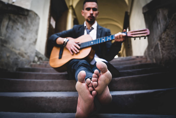 Straßenmusiker, der draußen Gitarre spielt. Selektiver Fokus auf die Füße. Musik, Kunst, Kreativität. - Foto, Bild