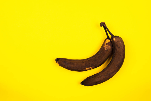 A top view of ripe dark bananas isolated on a yellow background - Foto, imagen
