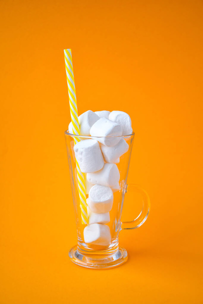 Glass cup bottle with marshmallows on a yellow background. Creative concept. Copy space. drinking straw - Foto, Imagem