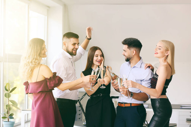 Молодые люди звонят бокалы вкусного шампанского на вечеринке в офисе - Фото, изображение
