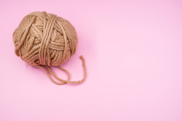 A high angle shot of a ball of yarn on a pink surface - Фото, изображение