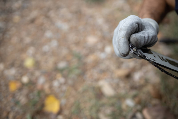 A closeup of a hand of a lumberjack with a chainsaw in a forest - 写真・画像